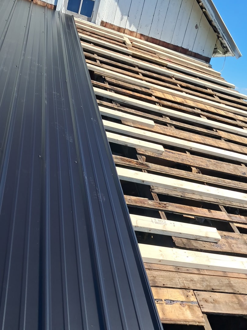 Metal roofing panels being installed over roof framing