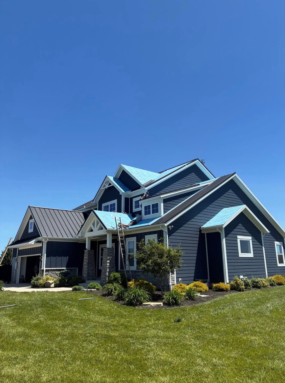 Metal roofing installation in progress on a blue home